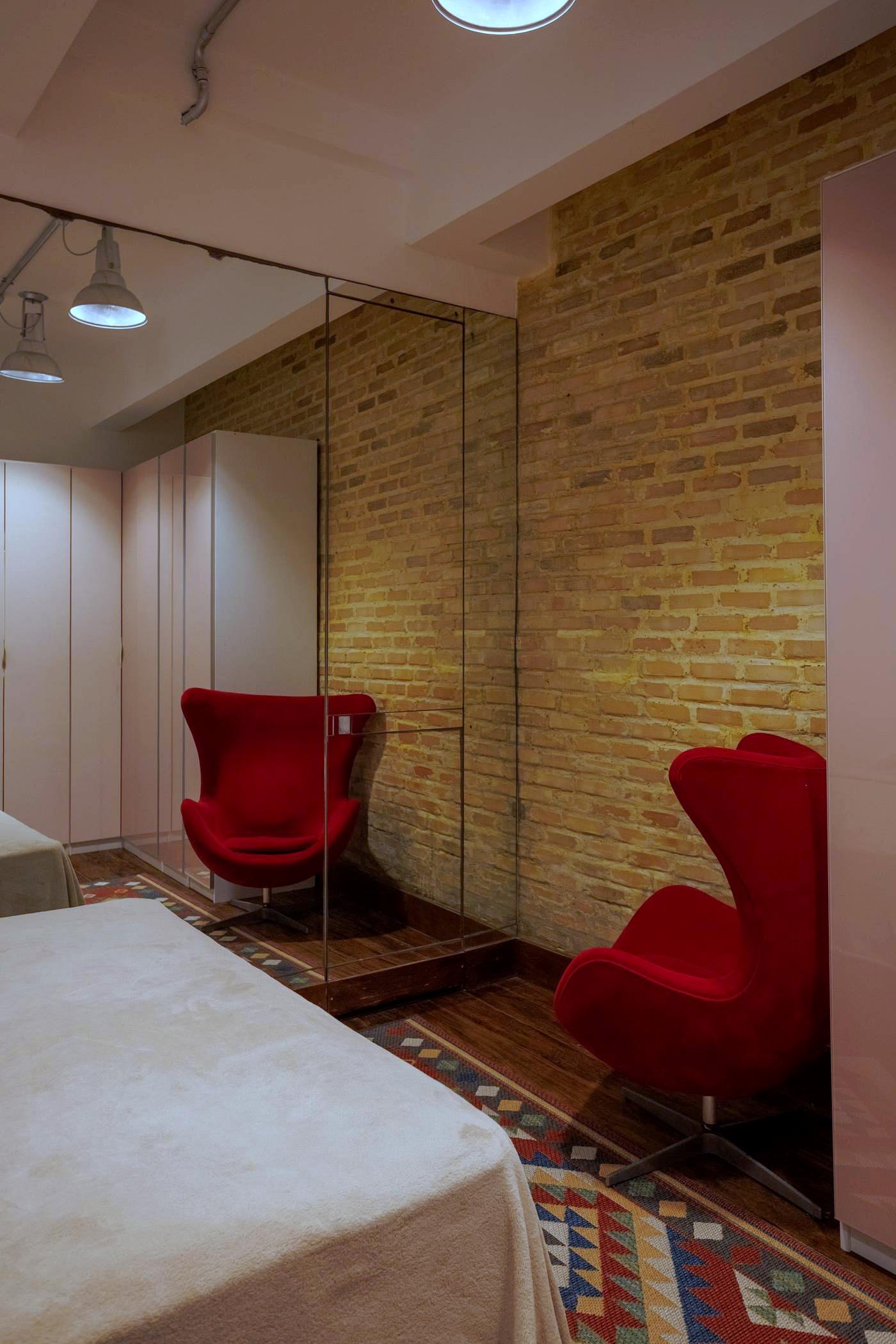 Quarto com poltronas de design e parede de tijolos